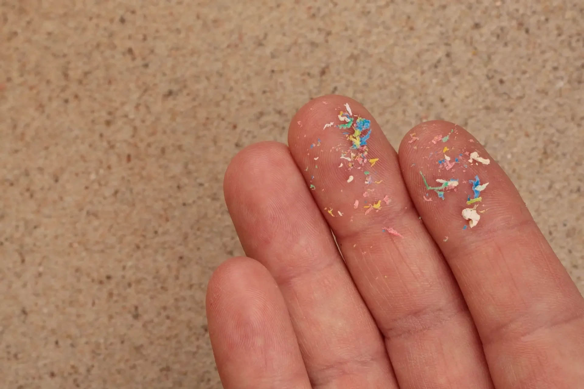 Close-up of fingers with colorful sprinkles on them.