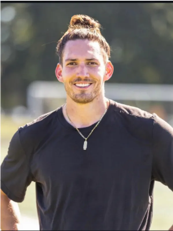 Smiling man in black t-shirt outdoors.